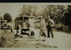 1925 Ford station wagon and men fixing flat tire